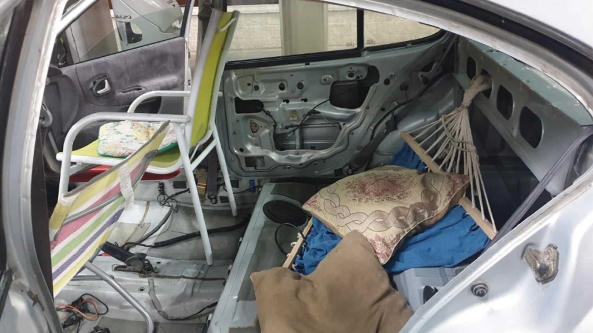 Interior de un vehículo que lleva sillas de playa y una hamaca en lugar de asientos