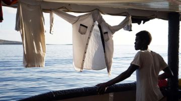 Un migrante mira desde la cubierta de el buque "Open Arms" las costas de Lampedusa (Italia)
