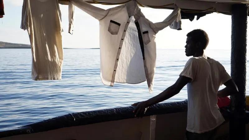 Un migrante mira desde la cubierta de el buque "Open Arms" las costas de Lampedusa (Italia)