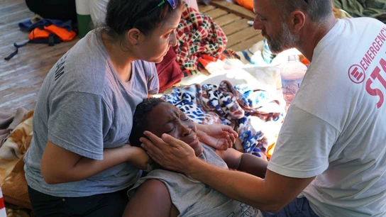 Dos sanitarios atienden a una de los 107 migrantes a bordo del Open Arms, fondeado frente a la costa de Lampedusa. Dos sanitarios atienden a una de los 107 migrantes a bordo del Open Arms, fondeado frente a la costa de Lampedusa.
