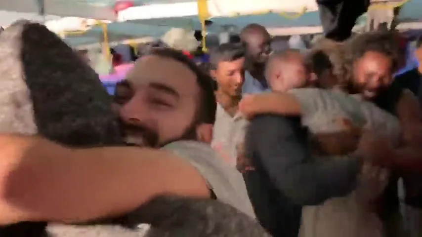 Abrazos, sonrisas y gritos de alegría en el Open Arms tras enterarse de que los migrantes desembarcarán en Lampedusa