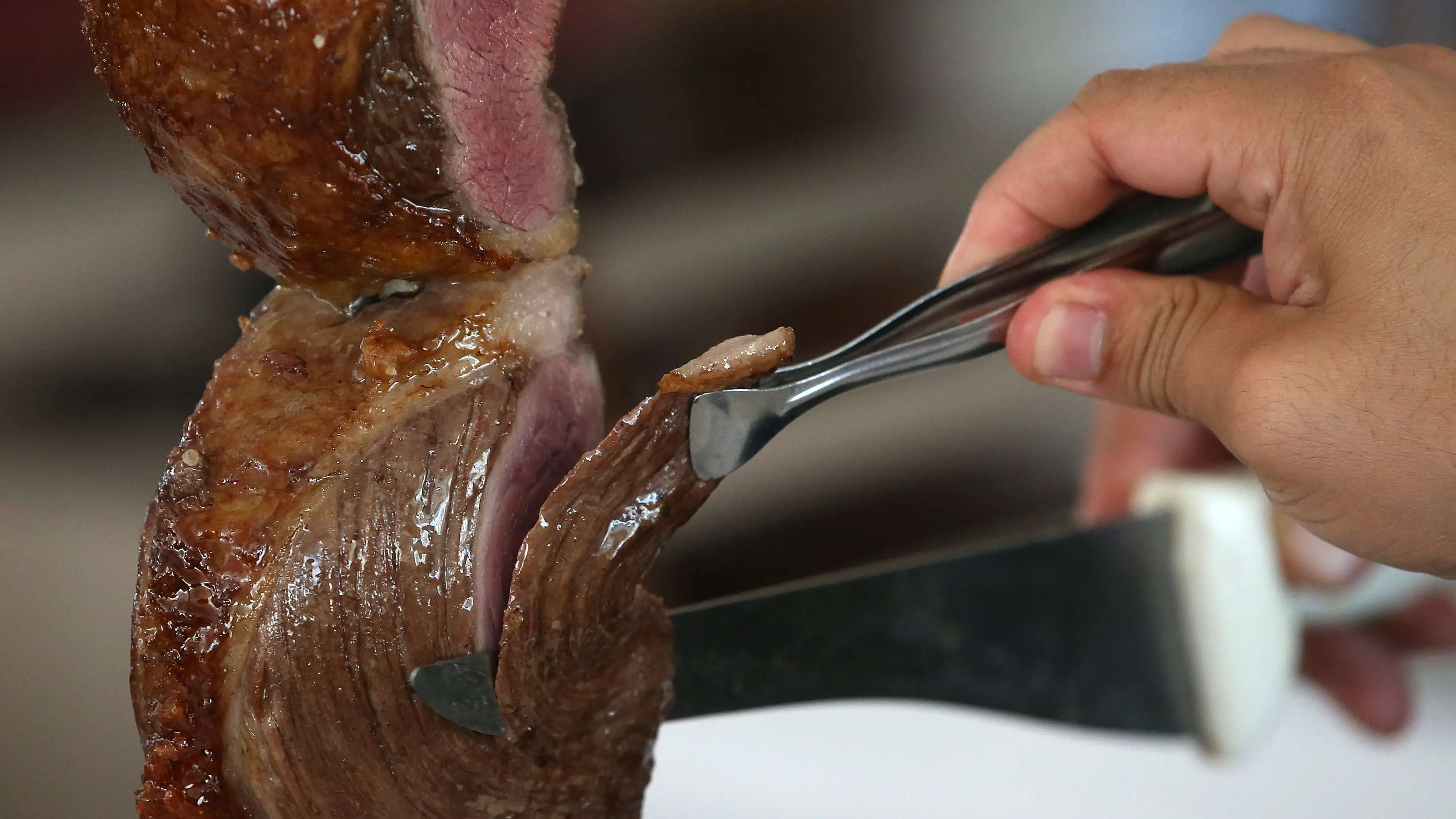 Una persona corta carne en una churrasquería