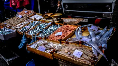 Mostrador de una pescadería con diferentes pescados expuestos en cajas.