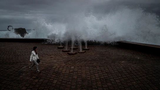Una mujer pasea en San Sebastián junto a la obra escultórica "El peine del Viento" Una mujer pasea en San Sebastián junto a la obra escultórica "El peine del Viento"