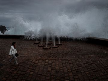 Una mujer pasea en San Sebastián junto a la obra escultórica "El peine del Viento" Una mujer pasea en San Sebastián junto a la obra escultórica "El peine del Viento"