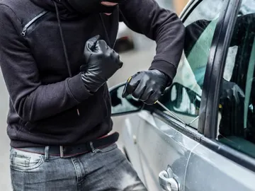 Un caco intentando robar un coche Un caco intentando robar un coche