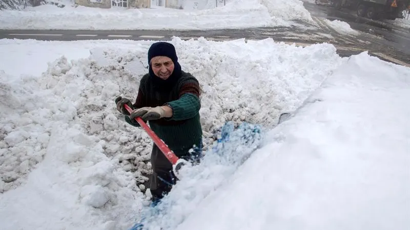 Un hombre retira la nieve sobre su vehículo en el alto del pueblo lucense de O Poio