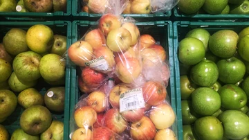 Manzanas en bolsas de plástico en un supermercado