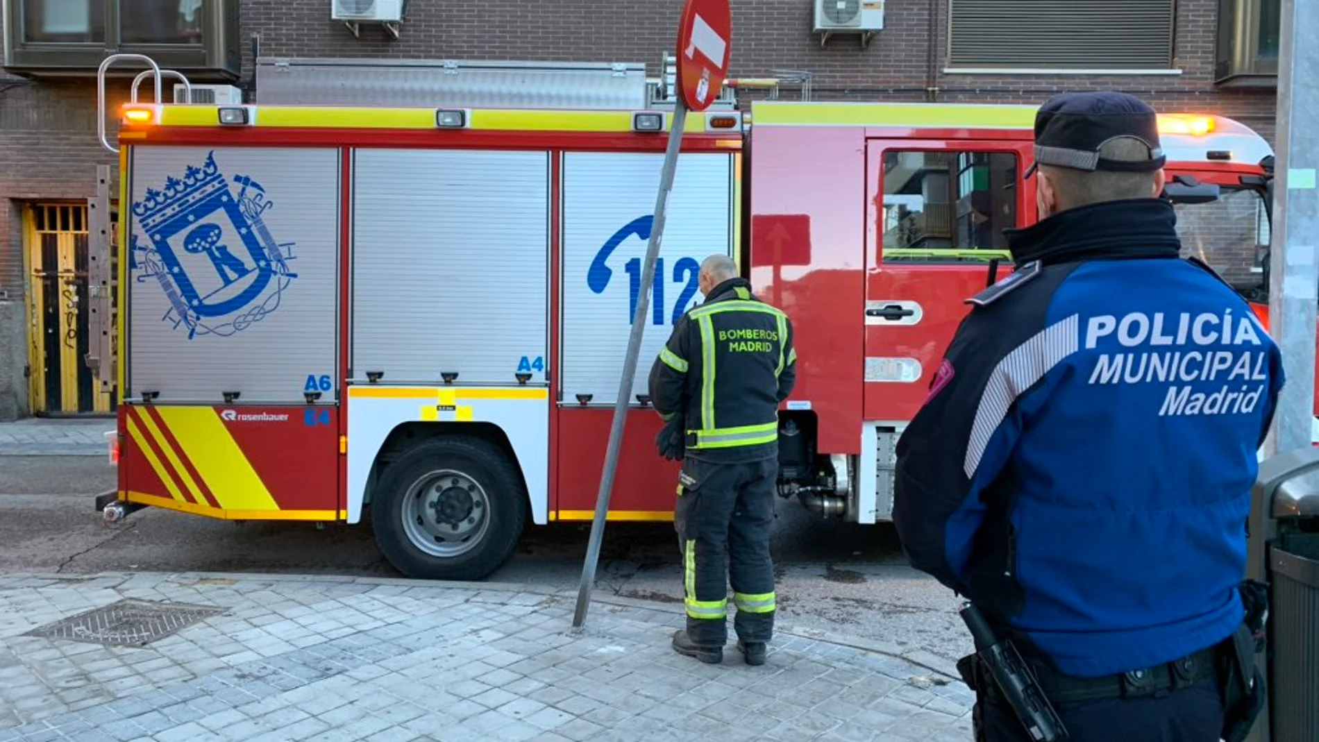 Un bombero y un policía tras el incendio declarado en Vallecas