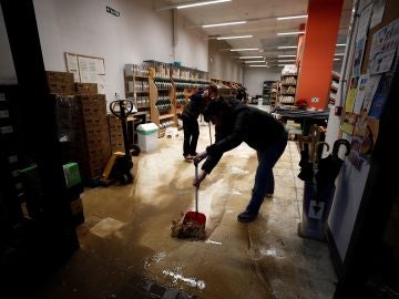 Varios empleados retiran agua y barro del interior de su comercio Varios empleados retiran agua y barro del interior de su comercio
