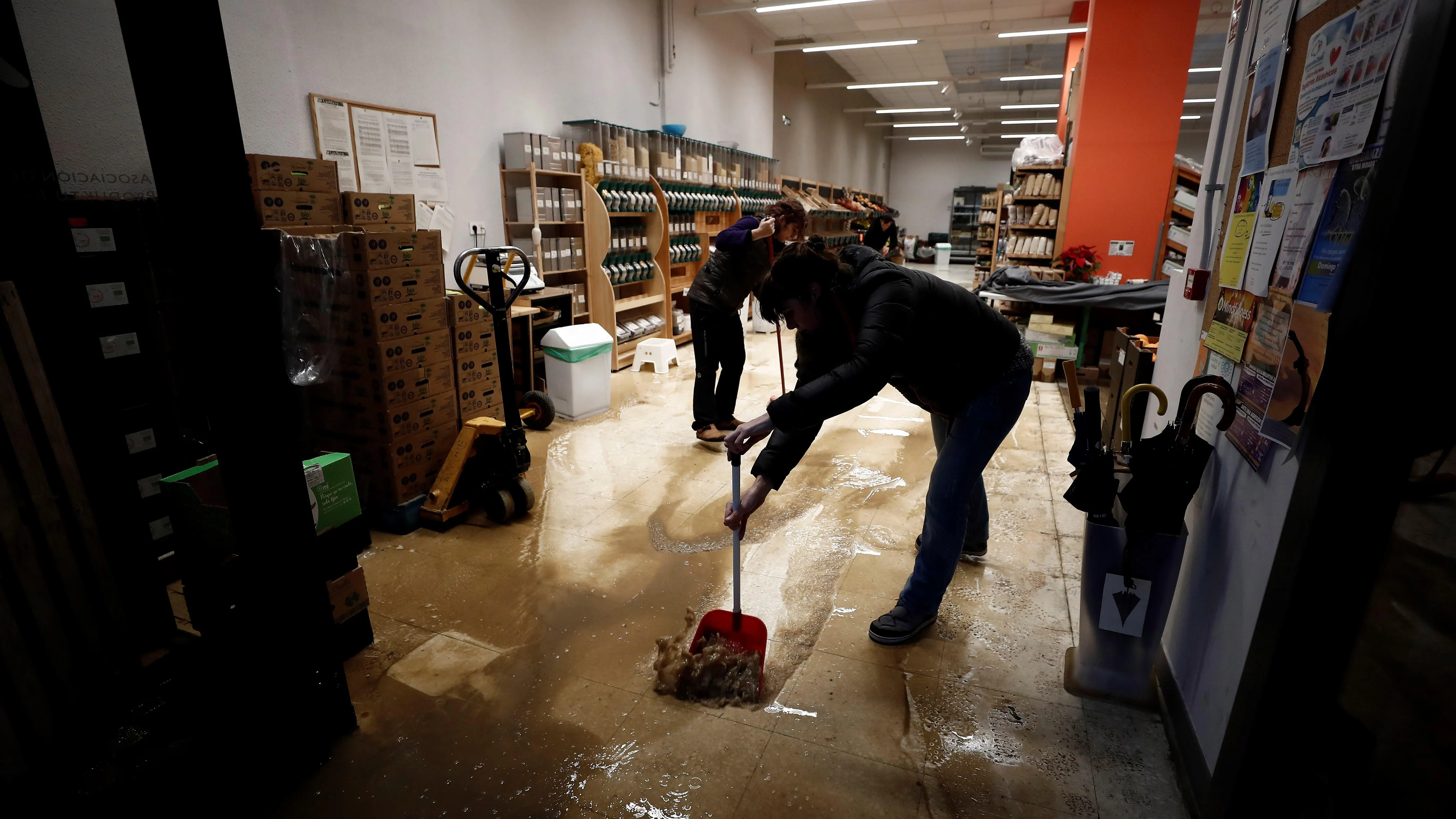  Varios empleados retiran agua y barro del interior de su comercio