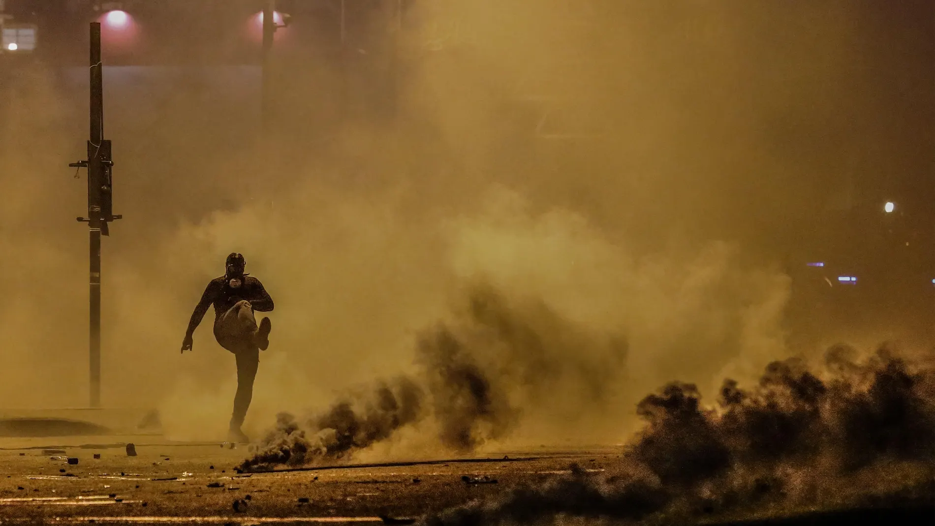Un manifestante da una patada a una granada de gas lacrimógeno