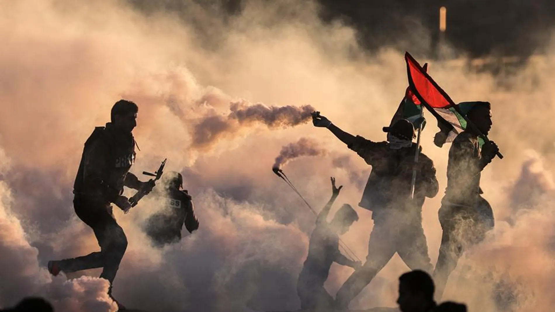  Los palestinos caminan a través del humo causado por las granadas de gas lacrimógeno israelíes 