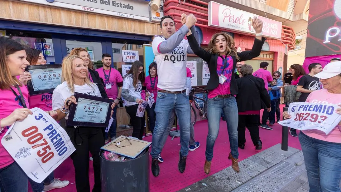 El representante de la administración de lotería El Perolo de San Pedro del Pinatar, Miguel Ángel Zapata (c) junto a varias trabajadoras de la administración celebran la venta del tercer premio