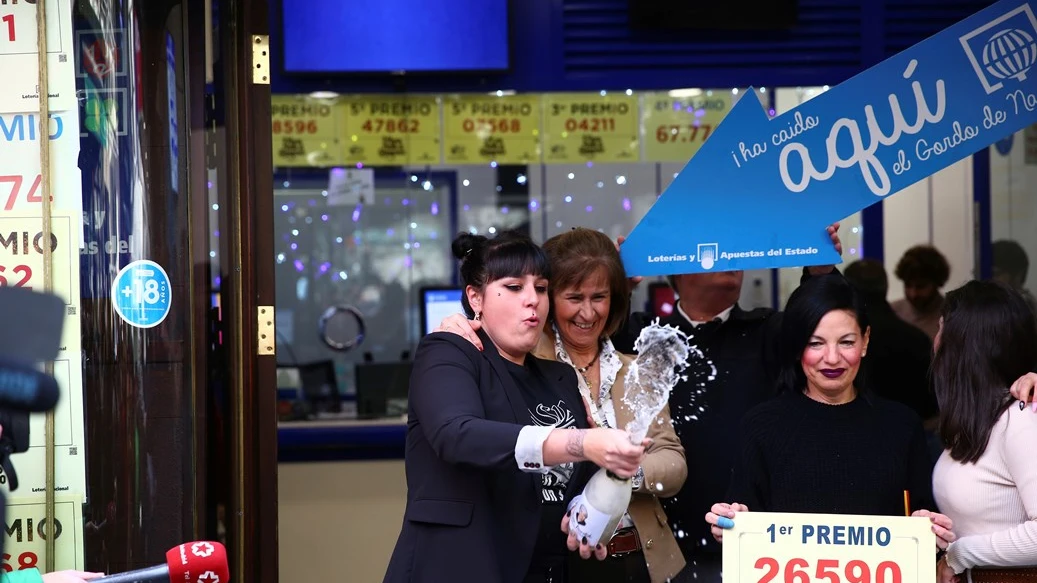 Un grupo de personas celebran en la administración madrileña de Doña Manolita que ha vendido el número 26.590