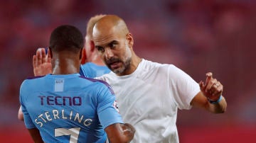 Guardiola habla con Sterling durante un partido