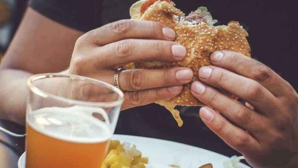 Imagen de archivo de un hombre comiendo una hamburguesa