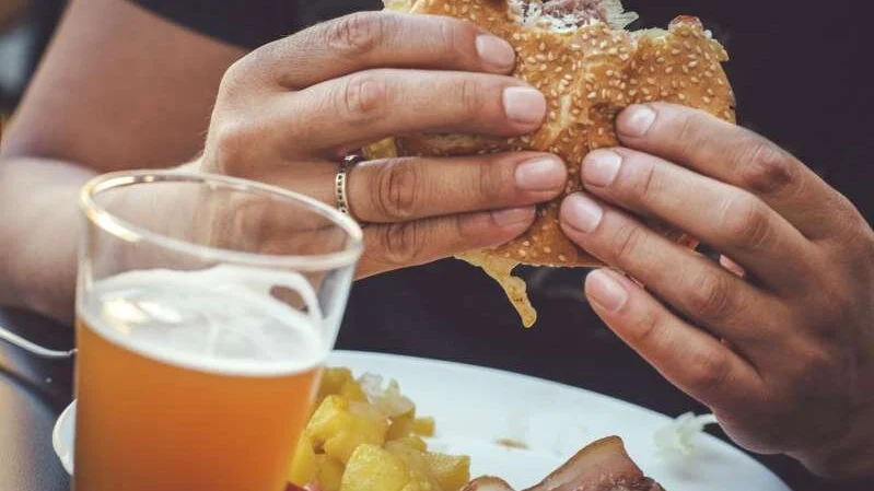 Imagen de archivo de un hombre comiendo una hamburguesa