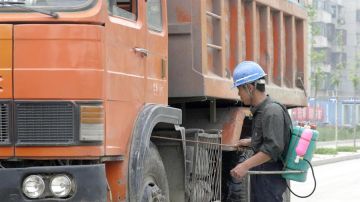 Imagen de un trabajador desinfectando los bajos de un camino en Pekín, China. 