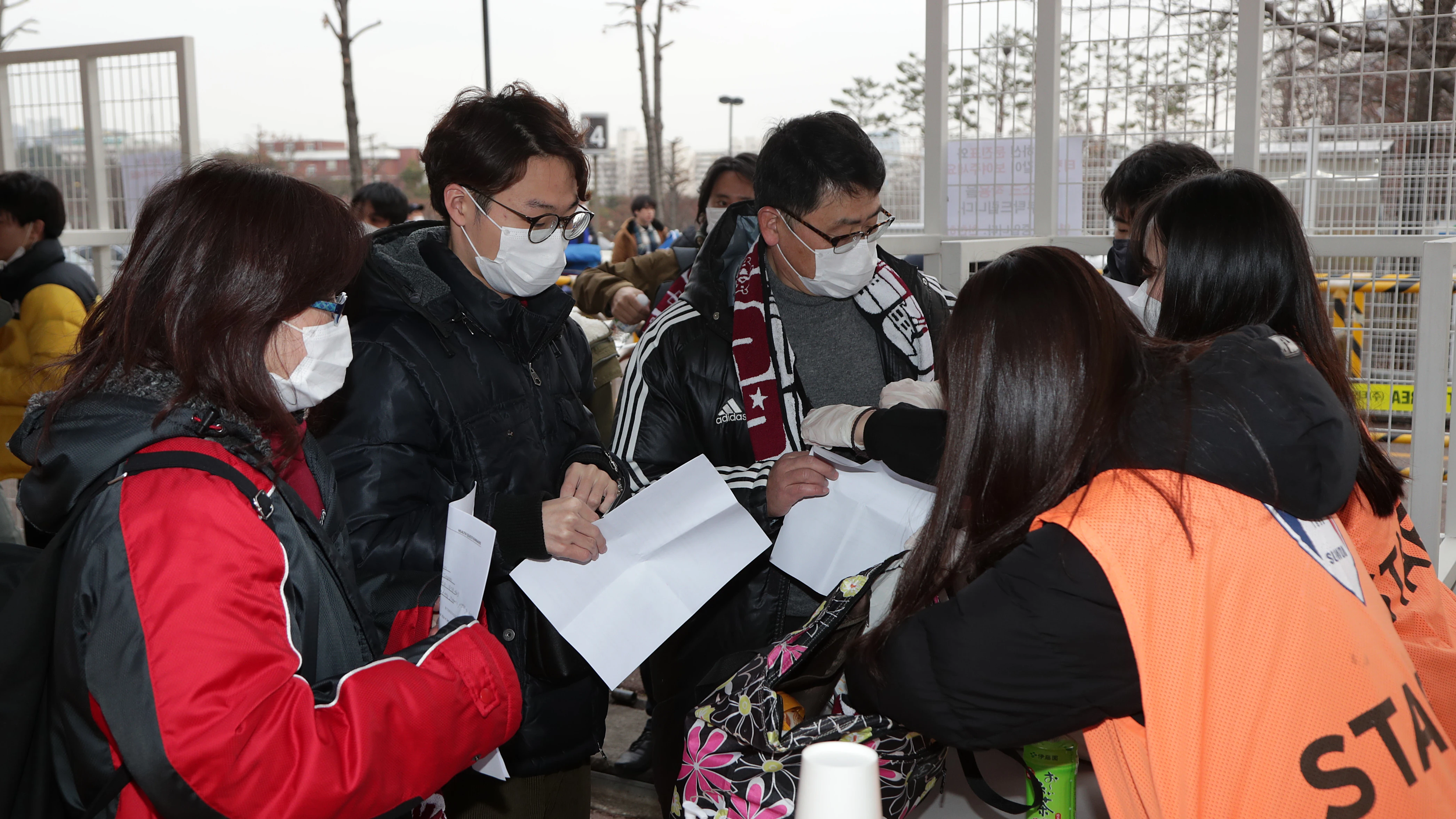 Aficionados entrando a un partido de fútbol protegiéndose del coronavirus