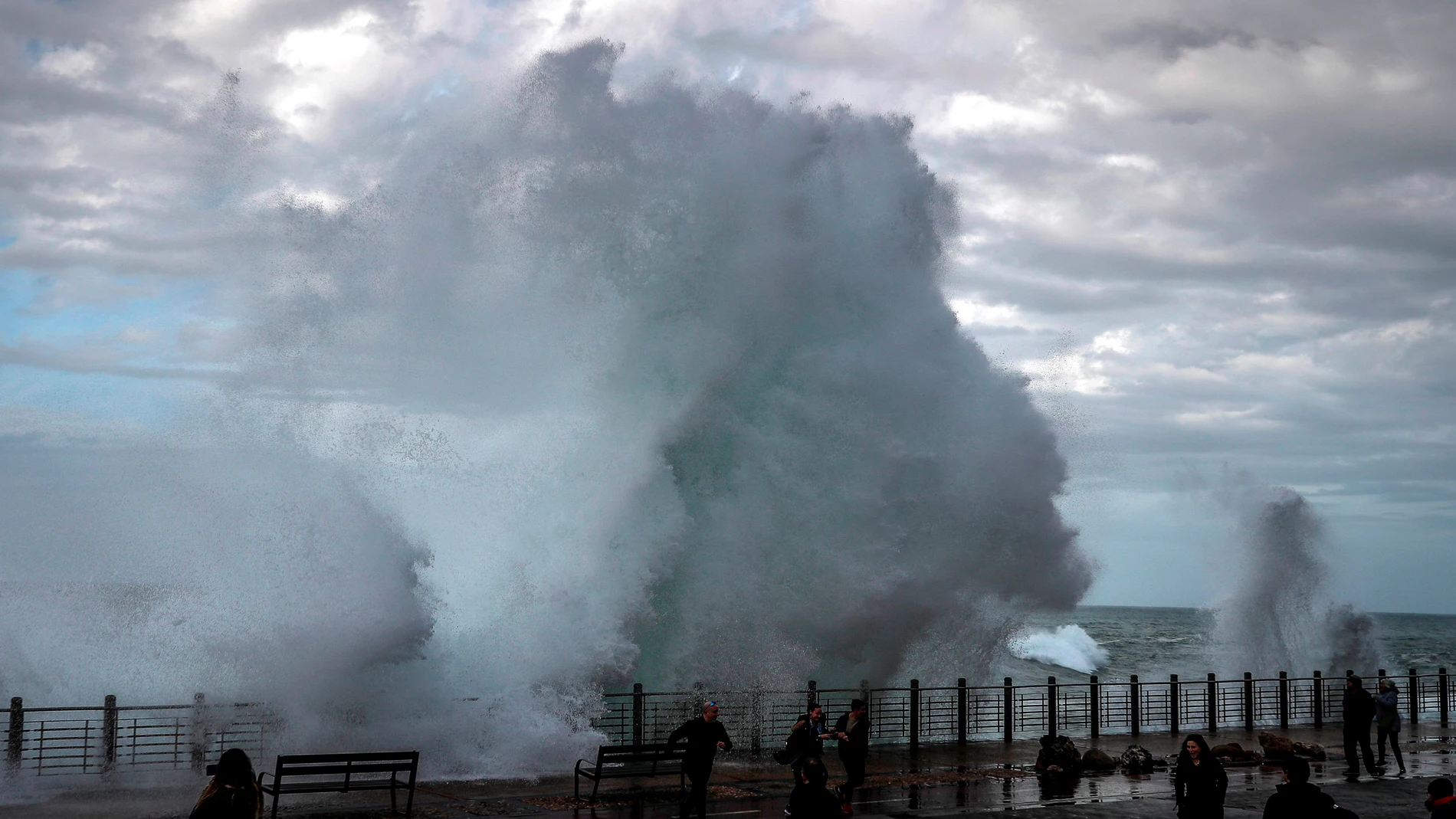 Varias personas son sorprendidas por una gran ola rompiendo en el Paseo Nuevo de San Sebastián
