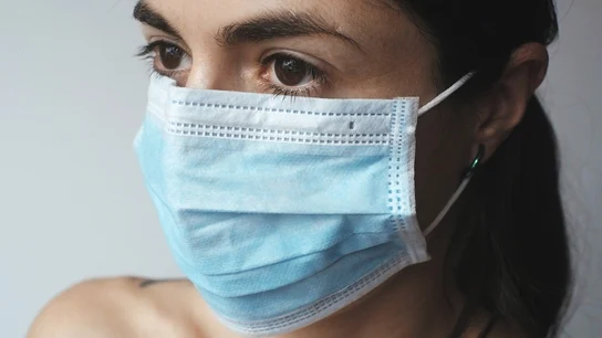 Una mujer con una mascarilla quirúrgica Una mujer se protege del coronavirus con una mascarilla