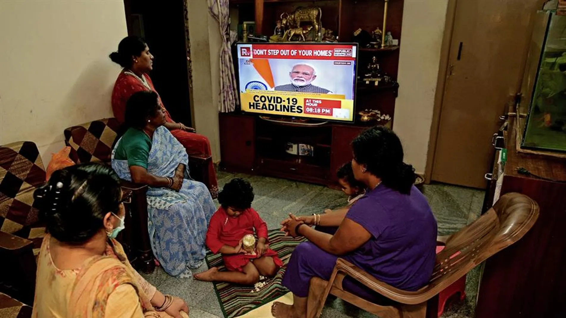 Una familia india escucha en la televisión el discurso del primer ministro sobre la alerta por COVID-19.