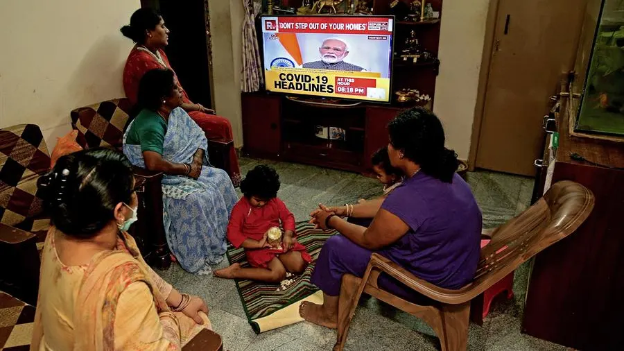 Una familia india escucha en la televisión el discurso del primer ministro sobre la alerta por COVID-19.