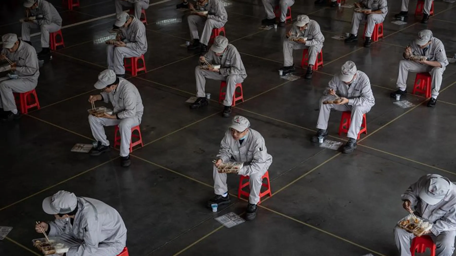 Trabajadores en una fábrica de Wuhan almuerzan guardando la distancia de seguridad por el coronavirus