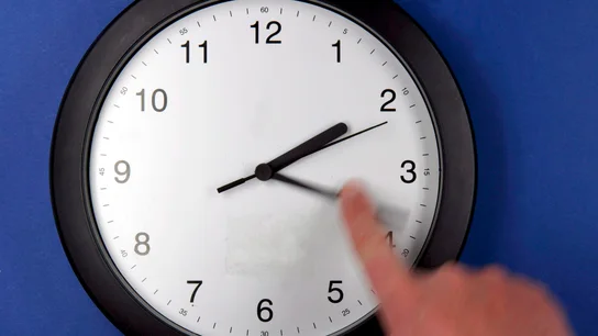 Una persona cambia la hora de un reloj Una persona cambia la hora de un reloj
