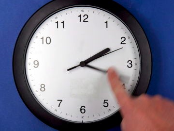 Una persona cambia la hora de un reloj Una persona cambia la hora de un reloj