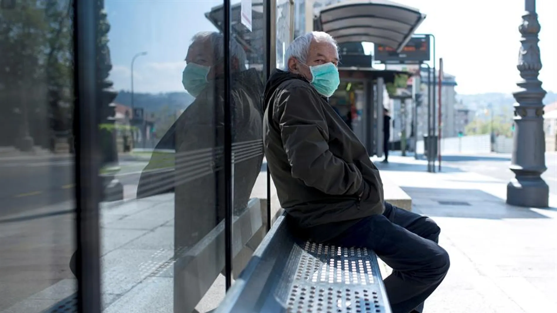 Un hombre con una mascarilla en una parada de autobús en Ourense.