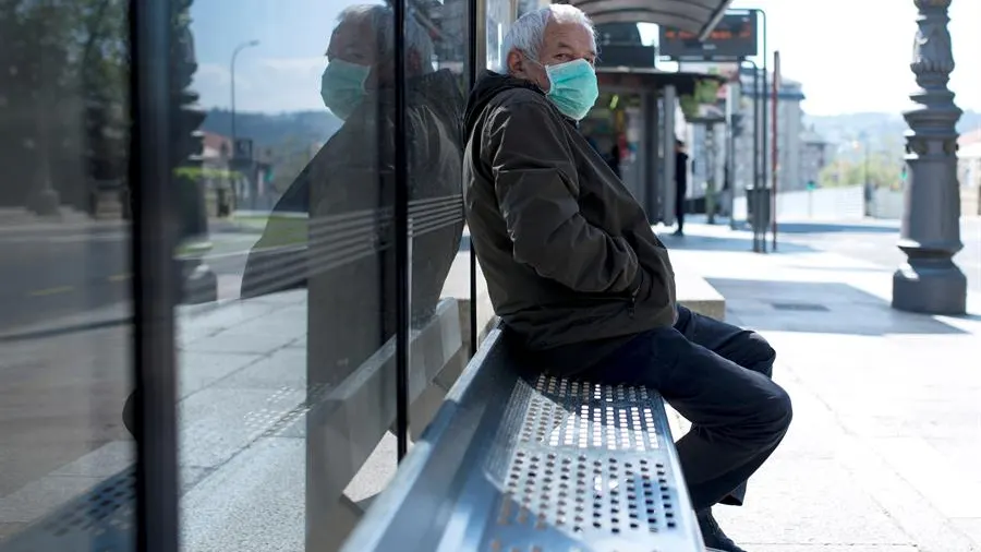 Un hombre con una mascarilla en una parada de autobús en Ourense.