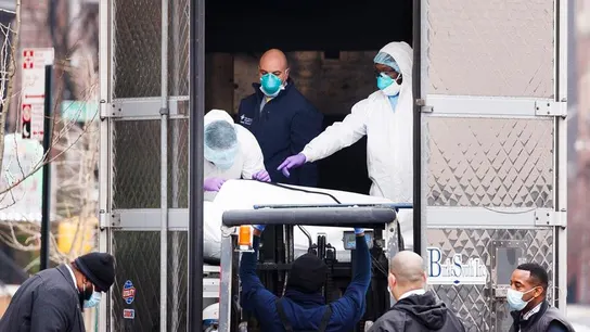 Foto de archivo de empleados trasladando un cuerpo a un camión empleado como morgue móvil Empleados del hospital trasladan un cuerpo a un camión empleado como morgue móvil