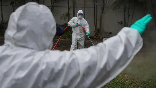 Los funcionarios de salud con trajes protectores rocían desinfectante. Los funcionarios de salud con trajes protectores rocían desinfectante.