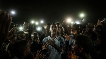 Un joven, iluminado por teléfonos móviles, recita poesía de protesta mientras los manifestantes cantan eslóganes que llaman a un gobierno civil, durante un apagón en Jartum, Sudán