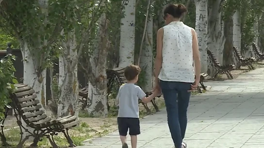 Una mujer pasea con un niño por la calle Una mujer pasea con un niño por la calle