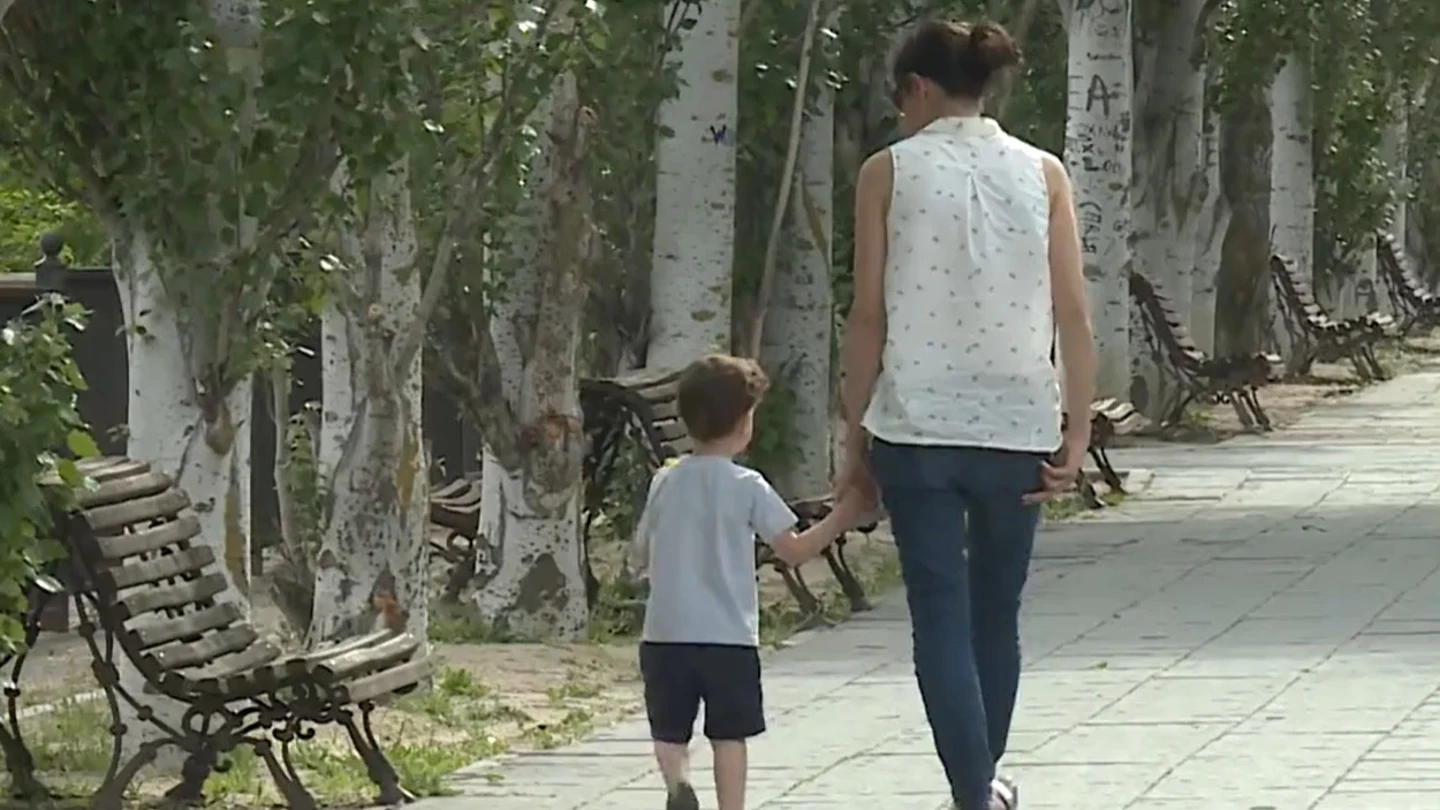 Una mujer pasea con un niño por la calle Una mujer pasea con un niño por la calle