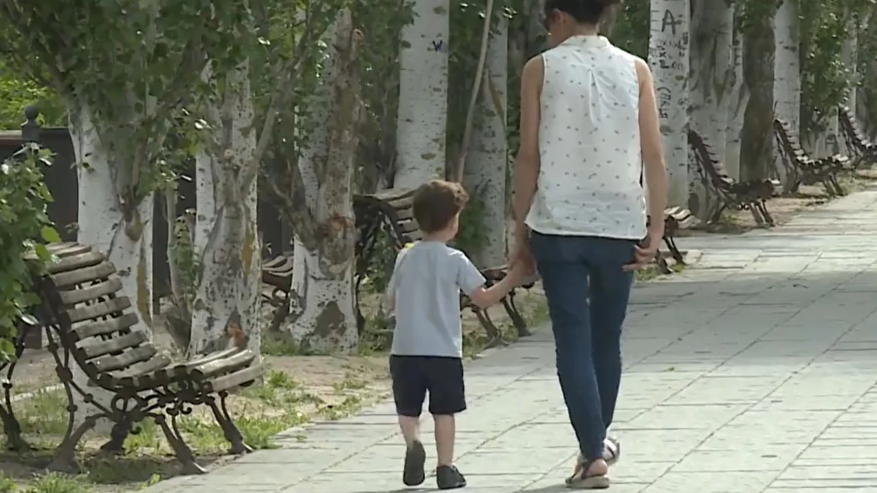 Una mujer pasea con un niño por la calle