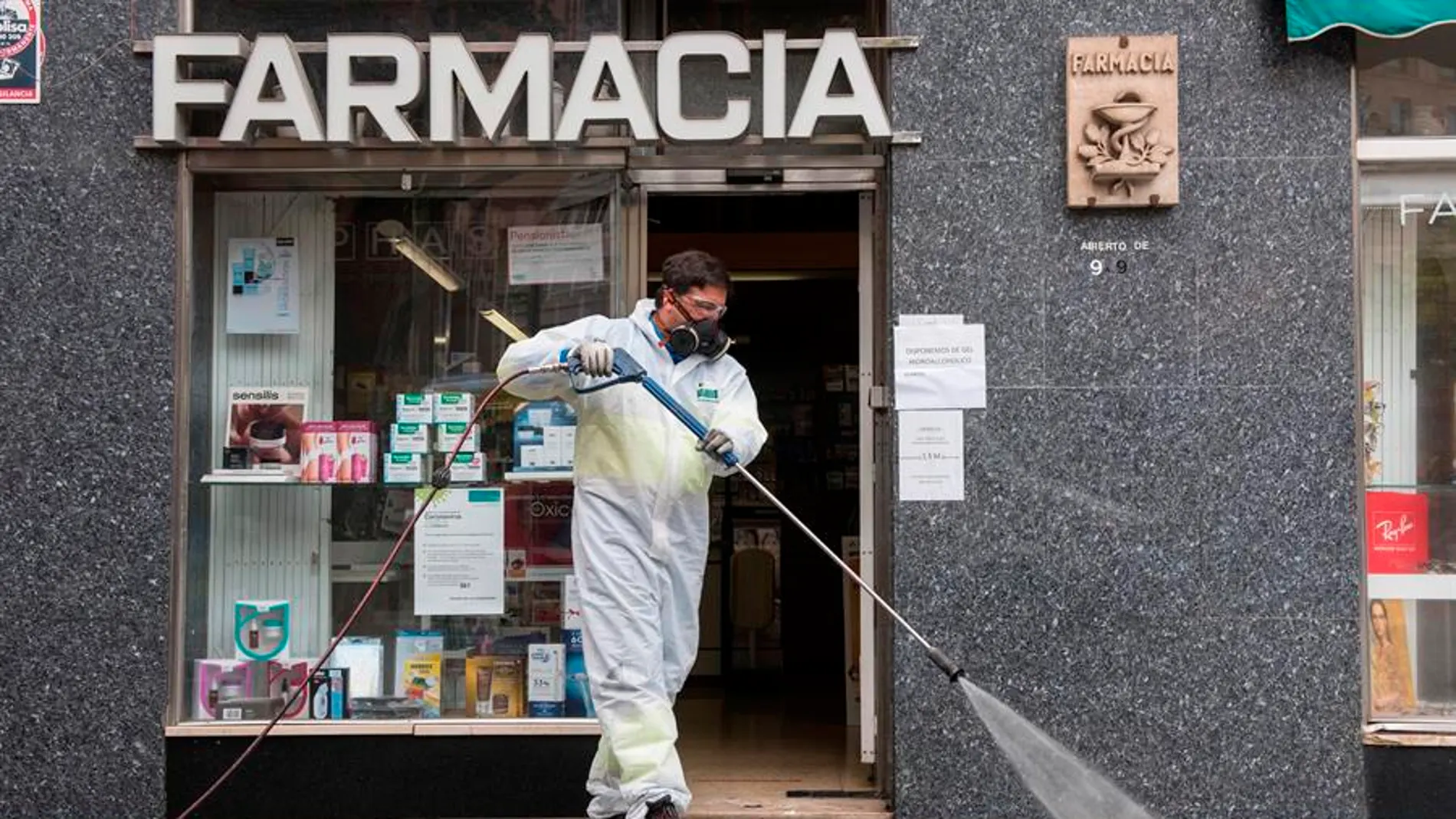 Un trabajador delimpieza desinfecta los alrededores de una Farmacia.