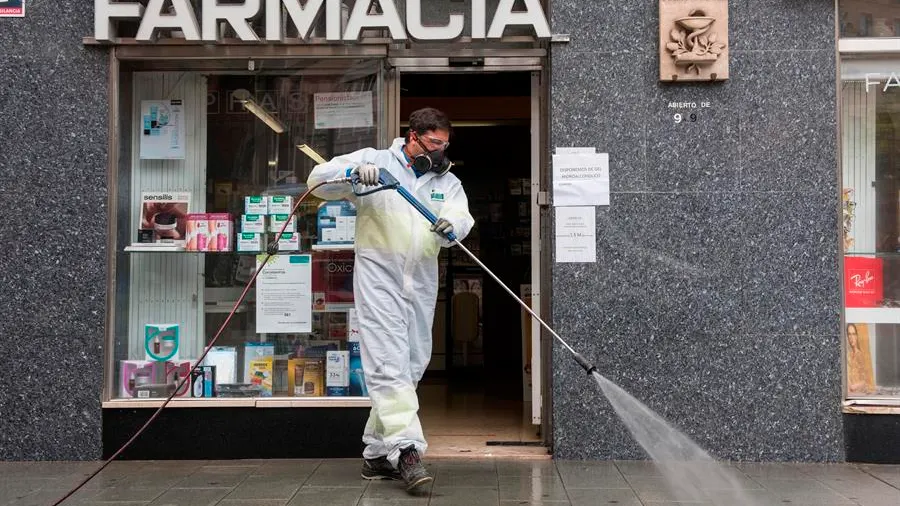 Un trabajador delimpieza desinfecta los alrededores de una Farmacia.