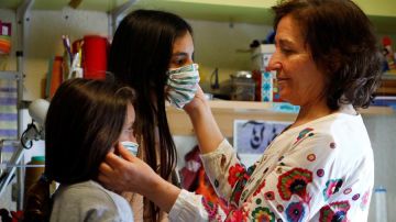 Una mujer prueba mascarillas a dos niñas