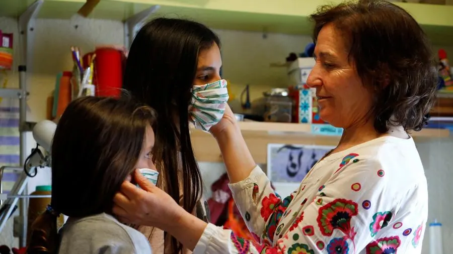 Una mujer prueba mascarillas a dos niñas