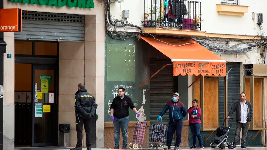 Varias personas hacen cola para entrar en un supermercado. 