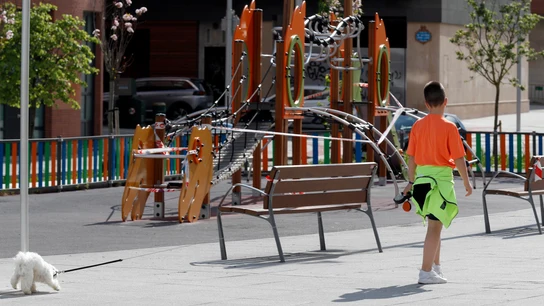 Un niño pasea el perro junto a un parque cerca de su casa en Bilbao COVID-19