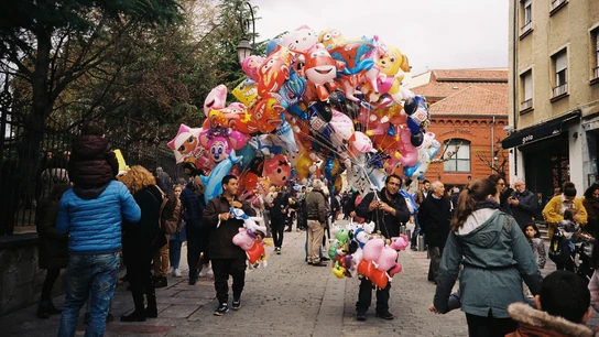 Un hombre vende globos de helio en la calle Feria
