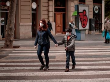 Una mujer acompañada de un niño cruza una calle en Valencia Una mujer acompañada de un niño cruza una calle en Valencia