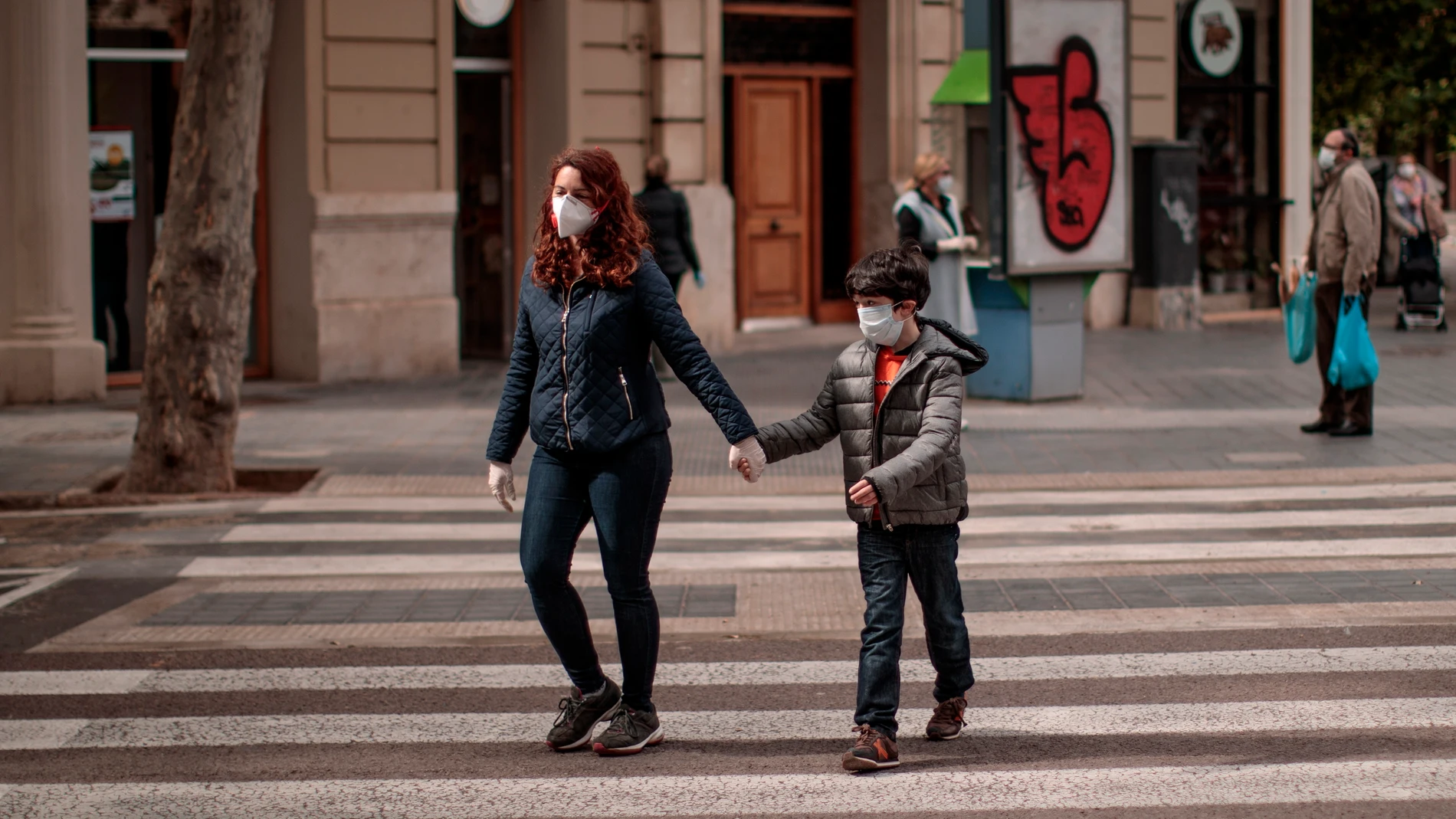  Una mujer acompañada de un niño cruza una calle en Valencia