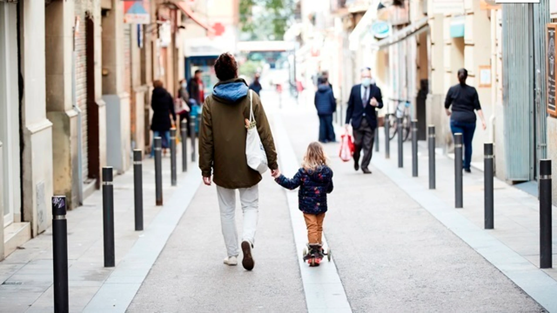 Un hombre y una niña caminan por el barrio de Gracia