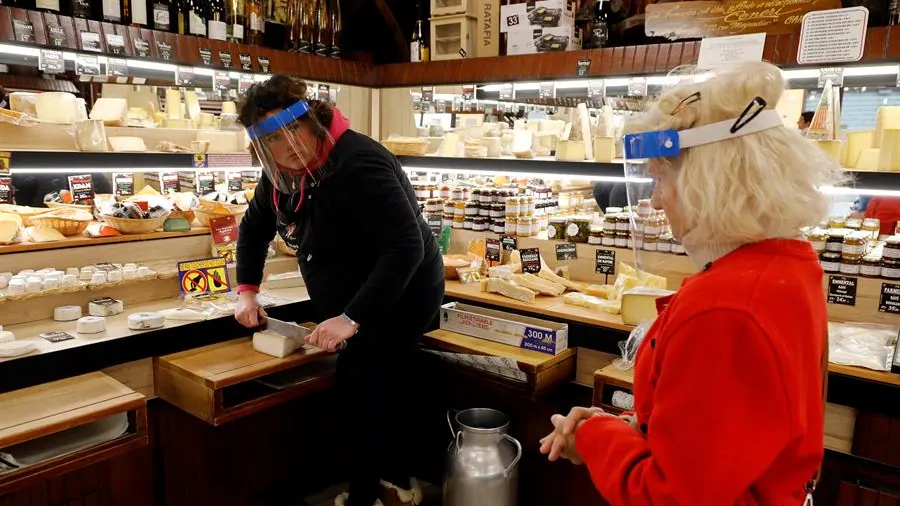 Una mujer compra en una tienda de quesos en Francia durante la pandemia de coronavirus